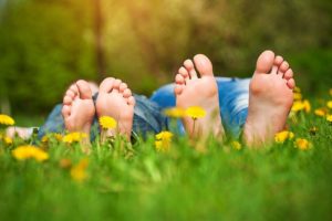 Photo of kid's feet, lying down in a field of grass.